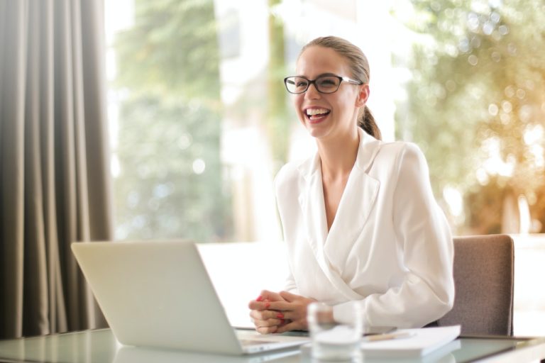 Lachende Frau mit Laptop im Büro beim Bewerber-Coaching
